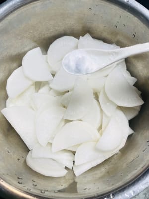 Marinasi dan Tiriskan:
Siapkan wadah bersih dan tuang lobak yang sudah ditiriskan. Tambahkan 1,5 sendok makan garam dan 1 sendok makan gula, aduk rata dengan tangan, lalu marinasi selama kurang lebih 15 menit agar lobak mengeluarkan cairannya.