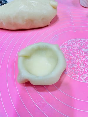 擀皮填餡：取一個劑子，像包餃子一樣擀成薄片，放入模具（冇雪媚娘定型模具也沒關係，用小巧的調味碗替代也可以）；先擠一層牛油，鋪奧利奧碎，再擠一層牛油；然後收口捏緊，用剪刀剪掉多餘“尾巴”，裝入紙托。