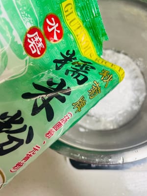 調麵糊：準備乾淨容器，依序加入 25g 玉米澱粉、70g 糯米粉、50g 白糖、135g 牛奶，用工具攪拌至無乾粉、順滑狀態。