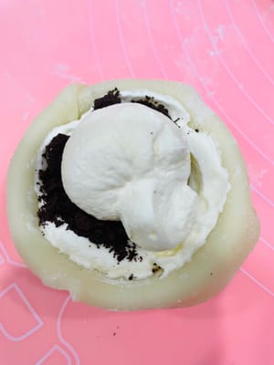 擀皮填餡：取一個劑子，像包餃子一樣擀成薄片，放入模具（冇雪媚娘定型模具也沒關係，用小巧的調味碗替代也可以）；先擠一層牛油，鋪奧利奧碎，再擠一層牛油；然後收口捏緊，用剪刀剪掉多餘“尾巴”，裝入紙托。