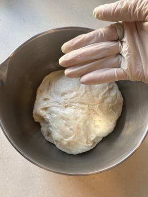 Preparémonos para el primer estiramiento y plegado. Empecemos humedeciendo las yemas de los dedos para que la masa no se pegue.