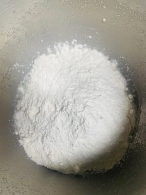 Add water and yeast to a bowl and mix well. Then add 500 grams of flour (reserve 80 grams for later use), salt and sugar and knead until the surface is smooth.