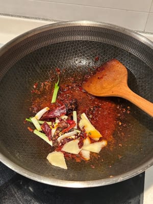 Then add in green onions, ginger, Sichuan pepper and dried chillies. Continue to stir fry until aromatic
