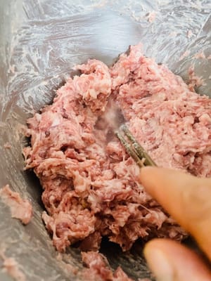 加入冰水:
分3次加冰水,每次加1/3,攪到肉把水全「吸」進去了再加下一次,全程得順著一個方向攪,攪到肉發黏、插根筷子能立住(這叫「上勁」,是Q彈的關鍵!不攪上勁煮出嚟就是散的)。