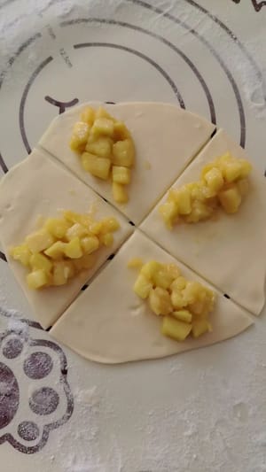 Einen Frühlingszwiebelpfannkuchen in 4 gleich große Teile teilen, die Apfelfüllung in die Mitte geben, von beiden Seiten halbieren und dann mit einer Gabel festdrücken.