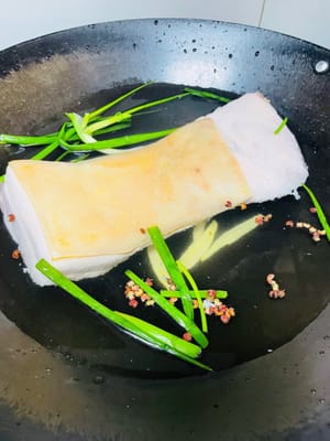 Sbollentare la pancetta di maiale
Mettere la pancetta di maiale pulita in una pentola di acqua fredda. Aggiungere i grani di pepe di Sichuan, i cipollotti, le fette di zenzero e il vino da cucina. Portare l'acqua a ebollizione e cuocere a fuoco lento per 20-30 minuti, finché non si riesce a infilare facilmente una bacchetta nella carne. Togliere dalla pentola e asciugare con carta assorbente.