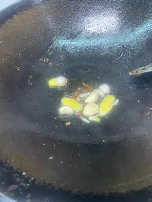 副菜の炒め物：フライパンに油を少し残し、さらに油を加えて、ニンニクのスライスとショウガのスライスを香りが立つまで炒め、次にピーマン、ニンジン、タマネギ、キクラゲを加えて、副菜に火が通るまで炒めます。