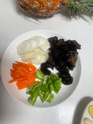 材料を準備します。ピーマン、ニンジン、ネギを刻み、ニンニクを潰し、ショウガを薄切りにします。辛いものがお好みなら、ニンジンを赤唐辛子に替えると、より鮮やかな色合いになります。