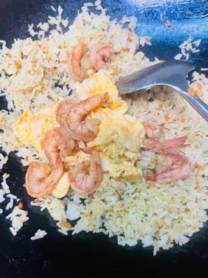 Añade el arroz y revuelve uniformemente. Luego agregamos los huevos previamente fritos y los camarones y continuamos salteando a fuego medio-bajo. El curry en sí contiene sal. Si consideras que no está suficientemente salado, puedes agregar una cucharadita pequeña de sal a tu gusto y saltear uniformemente. Luego servir.