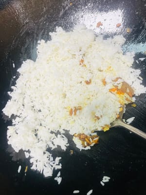 Añade el arroz y revuelve uniformemente. Luego agregamos los huevos previamente fritos y los camarones y continuamos salteando a fuego medio-bajo. El curry en sí contiene sal. Si consideras que no está suficientemente salado, puedes agregar una cucharadita pequeña de sal a tu gusto y saltear uniformemente. Luego servir.