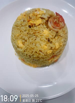 Añade el arroz y revuelve uniformemente. Luego agregamos los huevos previamente fritos y los camarones y continuamos salteando a fuego medio-bajo. El curry en sí contiene sal. Si consideras que no está suficientemente salado, puedes agregar una cucharadita pequeña de sal a tu gusto y saltear uniformemente. Luego servir.