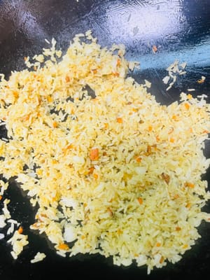 Añade el arroz y revuelve uniformemente. Luego agregamos los huevos previamente fritos y los camarones y continuamos salteando a fuego medio-bajo. El curry en sí contiene sal. Si consideras que no está suficientemente salado, puedes agregar una cucharadita pequeña de sal a tu gusto y saltear uniformemente. Luego servir.