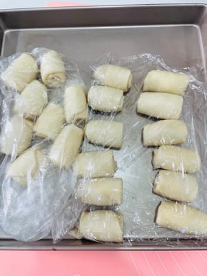第二次擀油酥皮及醒面
第二次，將捲好的蛋黃酥生麵團，在中間壓扁一下，再擀長至10cm左右，再捲起嚟，蓋上保鮮膜醒面10分鐘備用。
注意：擀皮時上下推開，勿嚟回擀，輕力操作，皮別太薄，以免破酥。