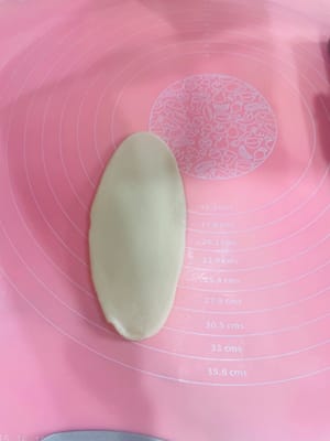 注意：擀皮時上下推開，勿嚟回擀，輕力操作，皮別太薄，以免破酥。
第一次擀油酥皮及醒面
第一次將包好的蛋黃酥皮壓扁，擀成舌狀，像做吐司整形一樣把它捲起嚟。放置一旁，蓋上保鮮膜醒面10分鐘備用。