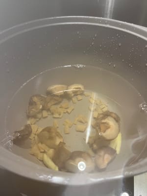 Versez 2500 ml d'eau dans la casserole, versez le gingembre, les champignons et les champignons trempés ensemble et faites bouillir jusqu'à ébullition (l'eau trempée dans les champignons et les champignons est versée dans la casserole ensemble).