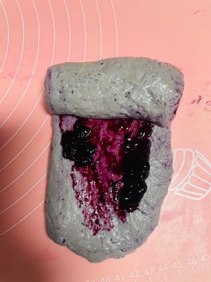 반죽을 꺼내 길게 밀어 편 후, 가운데에 블루베리 잼을 바르고 돌돌 말아 450g 토스트 틀에 넣습니다. 각 틀에 돌돌 말아 놓은 반죽을 3개씩 넣습니다. 방법은 영상을 참고하세요. (너무 질척거리고 끈적거리면 밀가루를 적당히 뿌려주세요. 너무 많이 뿌리지 마세요.)
