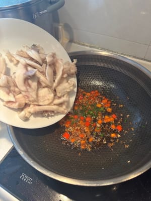然後加入煮熟的魚，繼續翻炒。最後關火，加入蔥花炒熟。