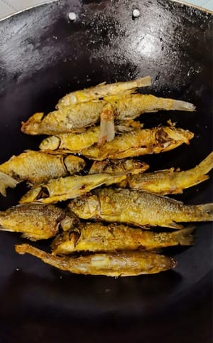 Goreng ikan sampai kedua sisi berwarna cokelat keemasan, tuangkan minyak berlebih dalam wajan, dan tambahkan air mendidih bersuhu 100 derajat.