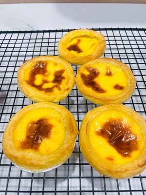 エッグタルトはオーブンから出したばかりで、泡がプクプクと音を立てていました。熱いうちに食べようと必死だったのですが、熱さで手が震えてしまいました。なんと、完璧な放物線を描いて「自由落下」したのです。皆さんにアドバイスです。熱いエッグタルトは急いで食べないでくださいね~
