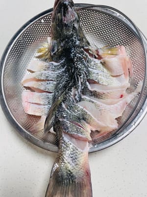 Il est préférable de demander à un poissonnier de découper le bar. Si vous découpez le poisson vous-même, lavez-le, égouttez-le et coupez-le à une profondeur modérée pour faciliter l'assaisonnement et la mise en forme lors de la friture.