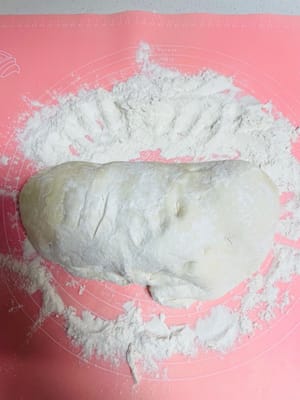 부풀어 오른 반죽을 꺼내어 다목적 밀가루를 넣고, 반죽의 공기 방울이 잘려나갈 때까지 여러 번 반죽합니다. 이 과정은 약 10분 정도 소요됩니다. 밀가루를 조금씩 넣어가며 반죽해 주세요. 인내심을 가지시기 바랍니다.