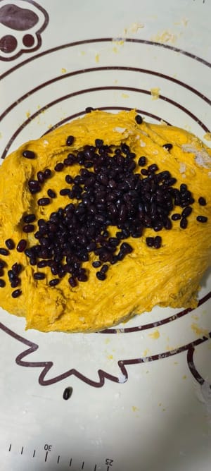 เมื่อหมักได้ที่แล้ว เทลงบนพื้นผิวสำหรับเตรียมอาหาร คลึงด้วยไม้คลึงแป้ง แล้วใส่ถั่วแดงลงไป