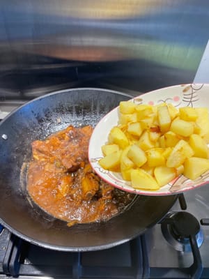 Après quinze minutes, ouvrez le couvercle du wok et ajoutez les pommes de terre frites. Bien mélanger.