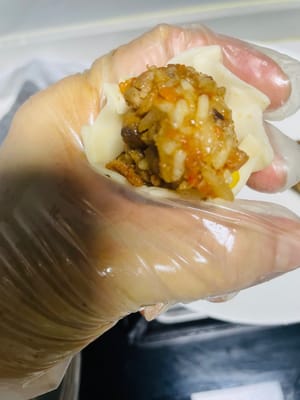Spread some water around the edge of the back of the dumpling wrapper and pinch it into five or six pleats (the more pleats, the less filling you can fit; the fewer pleats, the more filling you can fit. Which is your preference?). Add the glutinous rice filling.
Use your thumb and forearm to tighten the wrapper, pressing and pinching it firmly to prevent it from falling apart during steaming.