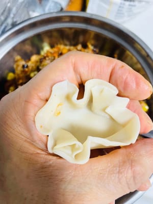 Spread some water around the edge of the back of the dumpling wrapper and pinch it into five or six pleats (the more pleats, the less filling you can fit; the fewer pleats, the more filling you can fit. Which is your preference?). Add the glutinous rice filling.
Use your thumb and forearm to tighten the wrapper, pressing and pinching it firmly to prevent it from falling apart during steaming.