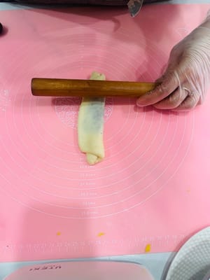 Ambil bola adonan yang sudah rileks, giling hingga berbentuk lembaran bulat, oleskan tipis pasta kacang merah di atasnya, gulung, giling sedikit lebih tipis, dan gulung lagi. Dengan cara ini, isian pasta kacang merah dapat tersebar lebih merata, tidak seperti saat membuat bakpao yang menggumpal di tengah dan terlalu manis saat digigit.