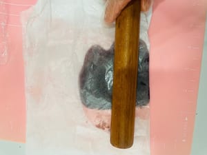 Bagi isian pasta kacang merah menjadi beberapa bagian kecil sesuai dengan jumlah bola adonan. Bentuk menjadi bola-bola, tutupi dengan kertas roti, dan pipihkan menjadi lembaran tipis dengan ukuran yang hampir sama dengan adonan roti. Sisihkan.