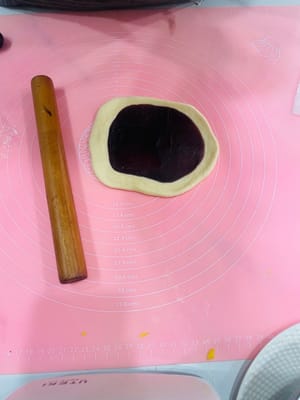 Ambil bola adonan yang sudah rileks, giling hingga berbentuk lembaran bulat, oleskan tipis pasta kacang merah di atasnya, gulung, giling sedikit lebih tipis, dan gulung lagi. Dengan cara ini, isian pasta kacang merah dapat tersebar lebih merata, tidak seperti saat membuat bakpao yang menggumpal di tengah dan terlalu manis saat digigit.