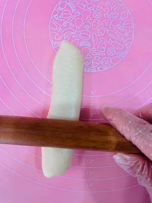 Ambil bola adonan yang sudah rileks, giling hingga berbentuk lembaran bulat, oleskan tipis pasta kacang merah di atasnya, gulung, giling sedikit lebih tipis, dan gulung lagi. Dengan cara ini, isian pasta kacang merah dapat tersebar lebih merata, tidak seperti saat membuat bakpao yang menggumpal di tengah dan terlalu manis saat digigit.