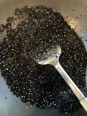 Den abgetropften Sesam in den Wok geben und bei mittlerer Hitze trocken braten.