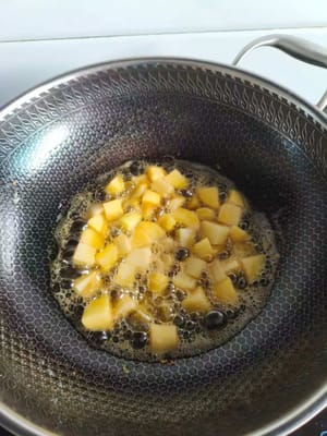 Panaskan minyak dalam wajan, masukkan 200 gram kentang potong dadu, goreng dengan api kecil.