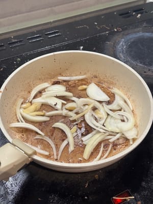 在同一个锅里，用五花肉分泌的油，翻炒洋葱片和大蒜，直到变软