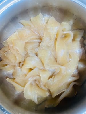 (Non cuocere troppo, altrimenti diventeranno molli.)
1. Portare a ebollizione una pentola capiente d'acqua. Aggiungere i noodles larghi ammollati e cuocere per 2-3 minuti. Usare le bacchette per testarne la cottura. Se non sono duri, toglierli.
2. Togliere i noodles e sciacquarli velocemente con acqua fredda (va bene anche l'acqua del rubinetto, non saltare questo passaggio). Scolare bene. Questo assicurerà che i noodles siano gommosi e non si attacchino tra loro.