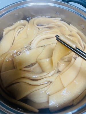 (너무 익히지 마세요. 너무 오래 익히면 질겨집니다.)
1. 큰 냄비에 물을 끓입니다. 불린 넓은 면을 넣고 2~3분간 삶습니다. 젓가락으로 면의 익힘 정도를 확인해 보세요. 딱딱하지 않으면 건져냅니다.
2. 면을 건져 찬물에 빠르게 헹굽니다(수돗물도 괜찮습니다. 이 과정을 생략하지 마세요). 물기를 완전히 빼주세요. 이렇게 하면 면이 쫄깃하고 서로 달라붙지 않습니다.