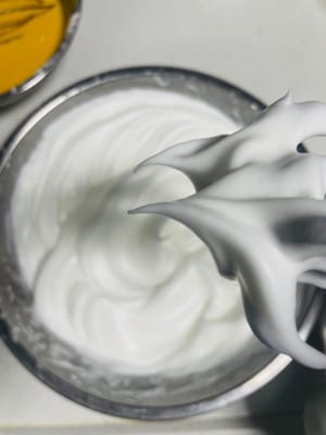 蛋白分阶段打发：
1启动打蛋器，低速打发蛋白，当出现大鱼眼泡（大泡 ）时，加入第一次白砂糖（约 1/3 量 ），继续打发。
2.随着打发进行，蛋白泡会变小变密，出现小泡泡时，加入第二次白砂糖（约 1/3 量 ），持续打发。
3.当蛋白变得浓稠、有光泽，接近湿性发泡（提起打蛋器，蛋白有小弯钩 ）时，加入第三次白砂糖，之后调为低档（如打蛋器的低速档 ）继续打发，整理气泡，使蛋白更稳定。
～综上，判断蛋白打发程度：打到打蛋器的钩上出现倒三角状蛋白，插入一根筷子，筷子能稳稳站立不倒，说明蛋白已打发到位（接近干性发泡，适合戚风蛋糕蓬松口感 ）。