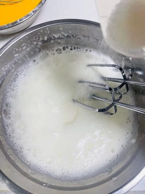 蛋白分阶段打发：
1启动打蛋器，低速打发蛋白，当出现大鱼眼泡（大泡 ）时，加入第一次白砂糖（约 1/3 量 ），继续打发。
2.随着打发进行，蛋白泡会变小变密，出现小泡泡时，加入第二次白砂糖（约 1/3 量 ），持续打发。
3.当蛋白变得浓稠、有光泽，接近湿性发泡（提起打蛋器，蛋白有小弯钩 ）时，加入第三次白砂糖，之后调为低档（如打蛋器的低速档 ）继续打发，整理气泡，使蛋白更稳定。
～综上，判断蛋白打发程度：打到打蛋器的钩上出现倒三角状蛋白，插入一根筷子，筷子能稳稳站立不倒，说明蛋白已打发到位（接近干性发泡，适合戚风蛋糕蓬松口感 ）。