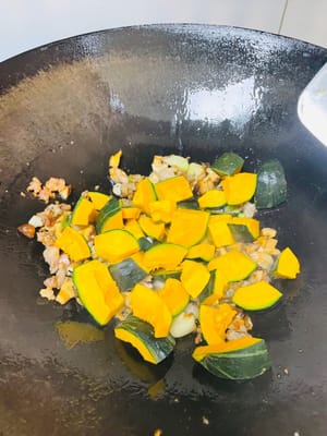 Tumis daging cincang hingga harum dan agak keemasan. Tambahkan 1 sendok makan lemak babi (atau 2 sendok makan minyak goreng). Masukkan daun bawang dan bawang putih, tumis hingga harum. Masukkan jamur shiitake yang telah dipotong dadu, tumis hingga harum. Kemudian, masukkan potongan labu dan tumis hingga rata.