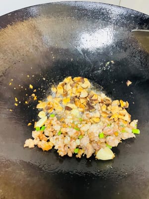 將肉沬翻炒出香、稍為發黃,加入豬油一大湯匙(或食用油2大匙)。依序加入蔥白、大蒜炒香,再放入冬菇顆粒翻炒,隨後加入南瓜塊翻炒均勻。