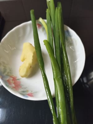 Continuiamo con il procedimento successivo: sbucciamo un pollice di zenzero e laviamo i cipollotti per preparare una salsa in cui intingere il pollo lesso in seguito. Se non vi piace, potete saltarla e sostituirla con un'altra salsa, amici.