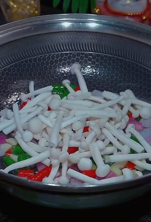 Calentar aceite en una sartén, añadir cebolla y sofreír hasta que desprenda aroma. Añadir chiles, jengibre, ajo y un poco de sal. Sofreír hasta que esté cocido. Luego, colocar una capa de hongos enoki rallados por encima.