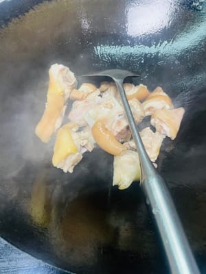 炒猪手上色
锅烧热加两勺食用油,倒入猪手翻炒到表面有点焦黄,加入姜片炒出香味,再从锅边淋入一勺料酒,接着依次加两勺生抽、一勺蚝油、一勺老抽,翻炒均匀。
炒到焦黄能让猪手更香,先加姜片炒香再淋料酒,能让姜香和酒香融合,更好地去掉腥味;生抽提鲜、蚝油增味、老抽上色,一步到位让猪手有底味又好看。