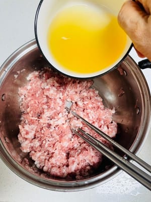 Relleno de carne cruda: Prepare el relleno de carne cruda mientras la carne marinada esté fría. Añade 2 cucharadas de salsa de soja ligera, 3 gramos de sal, 1 cucharada de salsa de ostras a 500 gramos de carne cruda y agrega 150 gramos de agua en 3 veces (usé agua remojada con granos de pimienta, jengibre y cebollas para realzar el sabor). Añade agua para evitar que el relleno quede seco (leñoso) y revuelve bien.