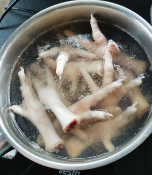 preparare una pentola, versare l'acqua, attendere che l'acqua bolla, quindi aggiungere le zampe di pollo.