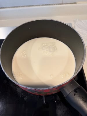 Tambahkan 320g susu dan 100g krim ke dalam panci dan nyalakan api kecil.