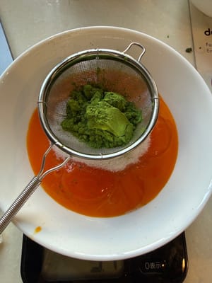 Ayak 10 gram bubuk matcha (disarankan untuk mencampur bubuk matcha terlebih dahulu dengan susu panas), lalu aduk rata.