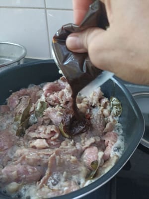 Unter Rühren braten, bis das Wasser austritt, dann ein Päckchen Rendang-Gewürzpaste (75 g) hinzufügen.